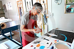 Detail of paint brushes and bright paint in an artistÃ¢â¬â¢s studio photo